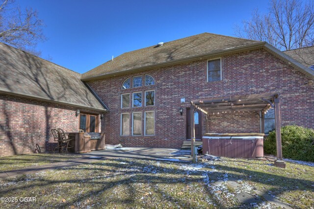 rear view of house with a pergola, a patio area, and a hot tub