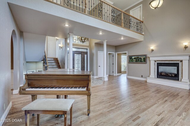 miscellaneous room featuring a fireplace, a high ceiling, light hardwood / wood-style flooring, and ornate columns