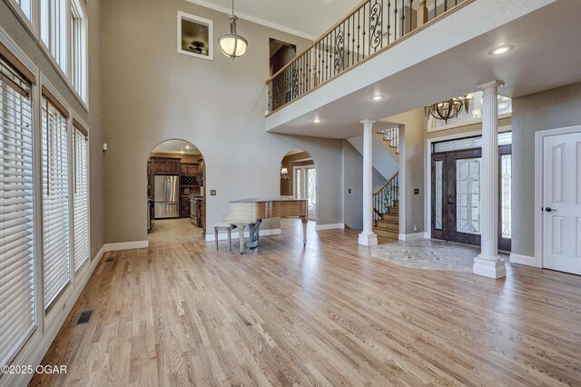 foyer with crown molding, light hardwood / wood-style flooring, a towering ceiling, and a healthy amount of sunlight