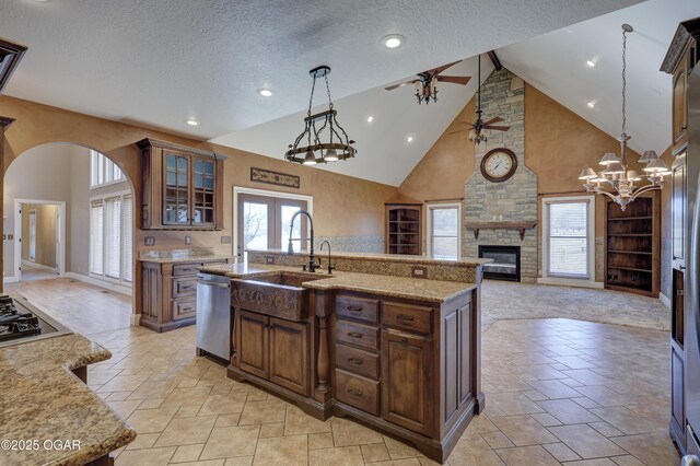 kitchen featuring a kitchen island with sink, high vaulted ceiling, stainless steel appliances, and a textured ceiling