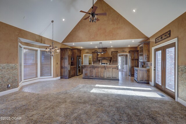 kitchen with high vaulted ceiling, a center island, hanging light fixtures, and stainless steel refrigerator