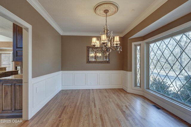 unfurnished dining area featuring light wood-type flooring, an inviting chandelier, and a healthy amount of sunlight