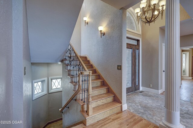 stairs featuring a high ceiling, an inviting chandelier, and ornate columns