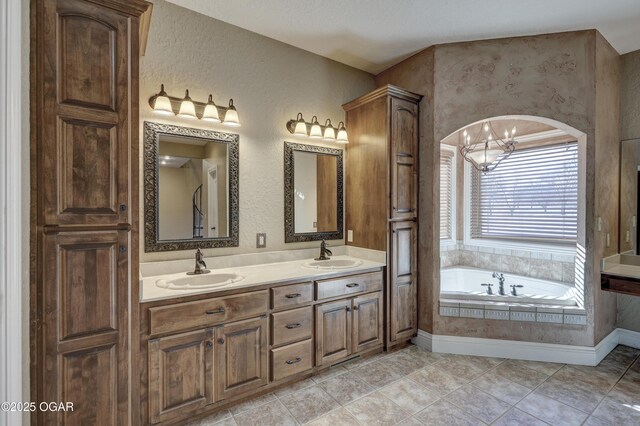 bathroom featuring tiled bath, tile patterned flooring, vanity, and a notable chandelier