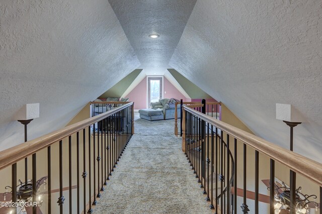 hall with lofted ceiling, carpet floors, and a textured ceiling