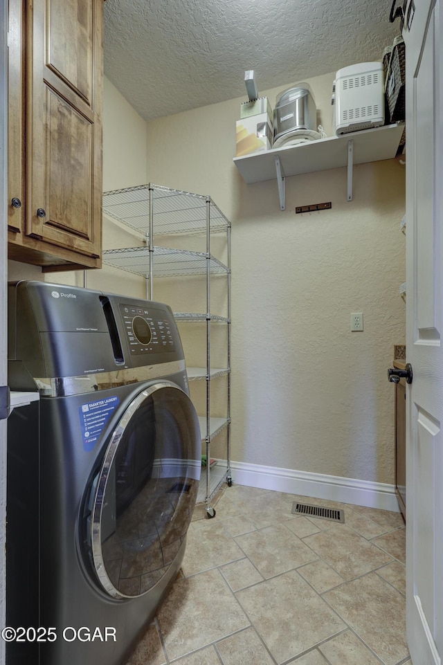 laundry area featuring cabinets and a textured ceiling