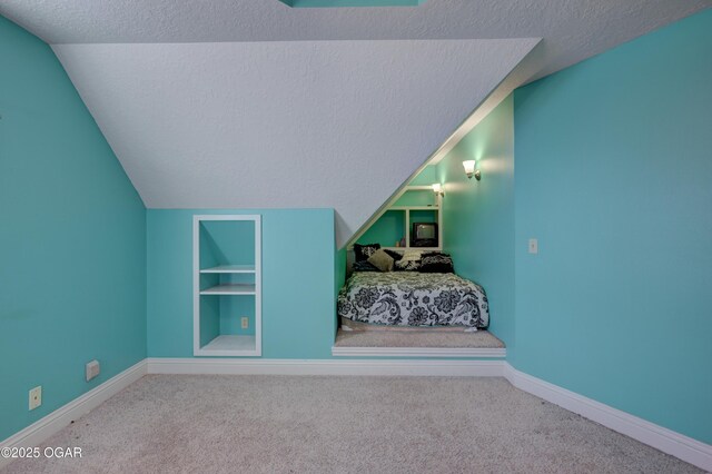 carpeted bedroom featuring lofted ceiling and a textured ceiling