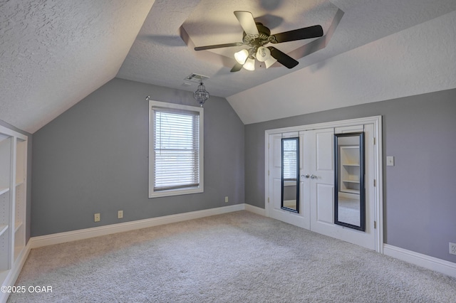 additional living space with light carpet, a textured ceiling, vaulted ceiling, and ceiling fan