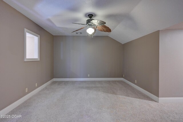 carpeted empty room with a textured ceiling, ceiling fan, and lofted ceiling