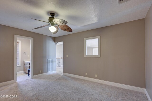 empty room featuring ceiling fan, light colored carpet, and a textured ceiling