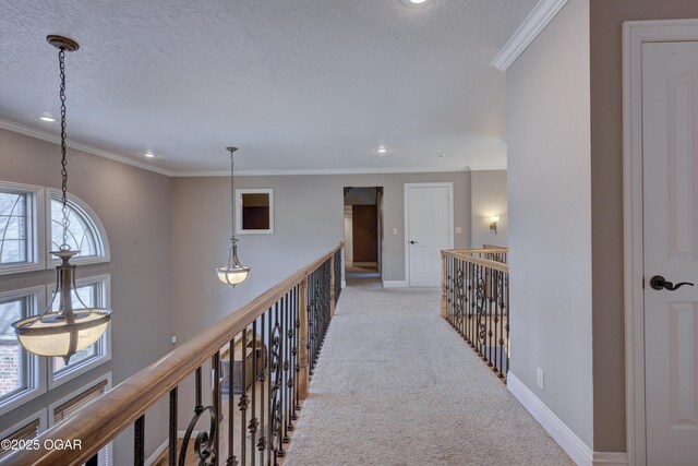 hall featuring light carpet, a textured ceiling, and ornamental molding