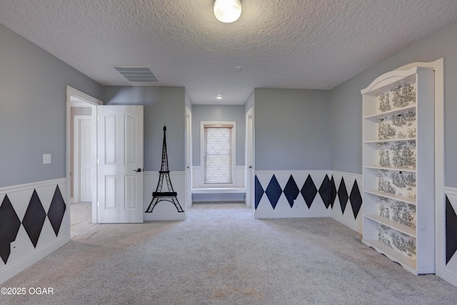 carpeted empty room featuring built in features and a textured ceiling