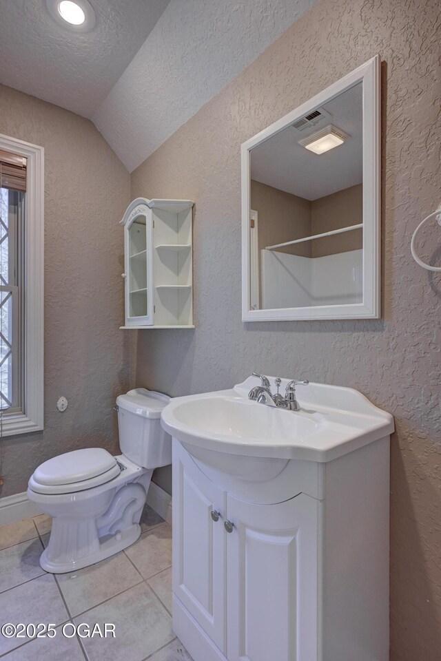 bathroom with vanity, a textured ceiling, tile patterned flooring, toilet, and lofted ceiling