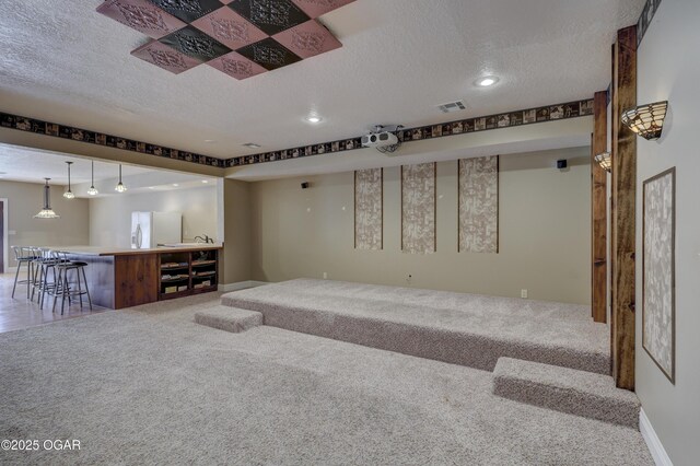 basement featuring carpet flooring, white refrigerator, a textured ceiling, and bar