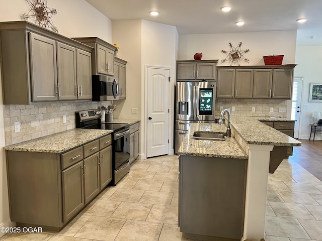 kitchen featuring a kitchen breakfast bar, appliances with stainless steel finishes, light stone countertops, light tile patterned floors, and sink