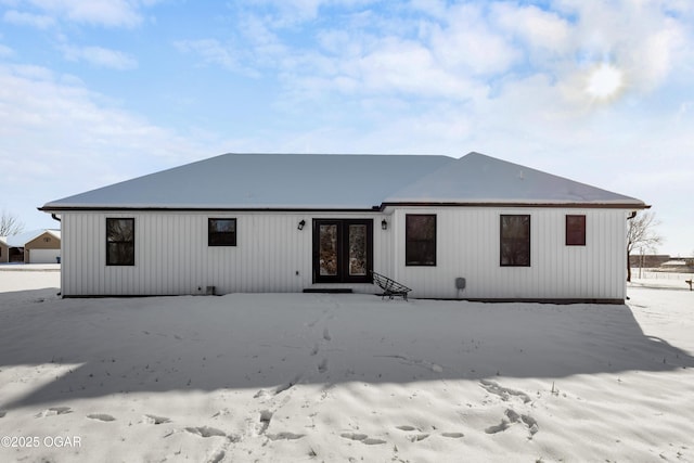 snow covered rear of property featuring french doors