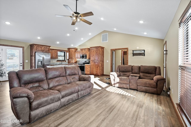 living room with ceiling fan, sink, light hardwood / wood-style floors, and lofted ceiling