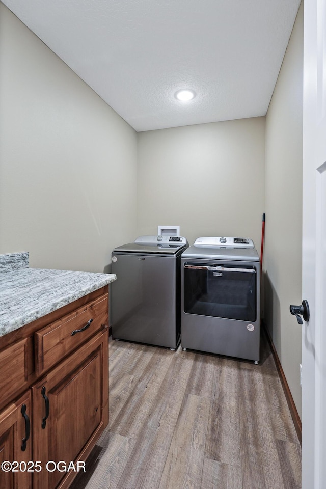 laundry area featuring cabinets, independent washer and dryer, and light hardwood / wood-style flooring