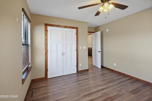 unfurnished bedroom with ceiling fan, a closet, and dark wood-type flooring