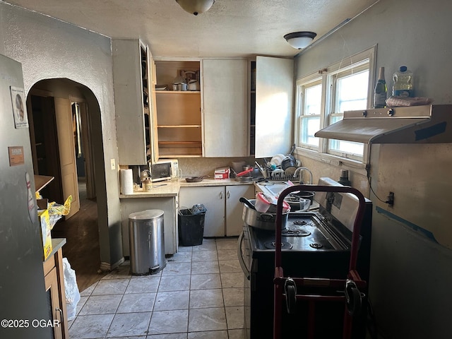 kitchen with light tile patterned floors, backsplash, and black stove