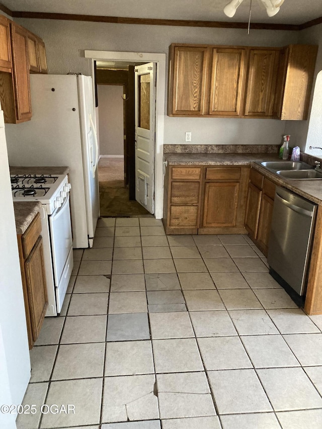 kitchen featuring white gas stove, dishwasher, sink, crown molding, and light tile patterned floors