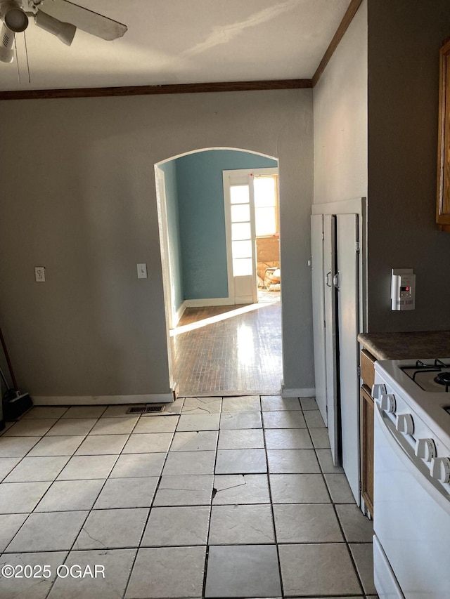 kitchen with range, light tile patterned floors, ceiling fan, and crown molding