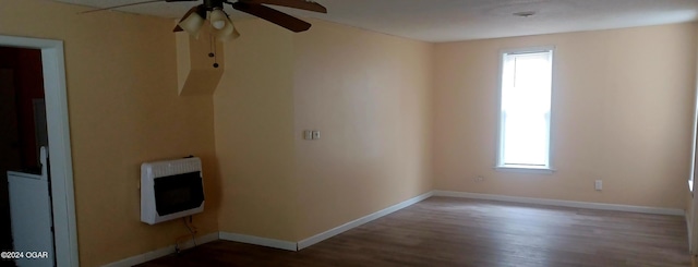 spare room with hardwood / wood-style floors, ceiling fan, a healthy amount of sunlight, and heating unit