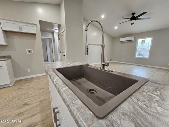 kitchen with white cabinetry, ceiling fan, a wall mounted air conditioner, and sink