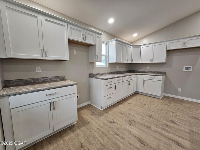 kitchen featuring vaulted ceiling, white cabinets, and light wood-type flooring