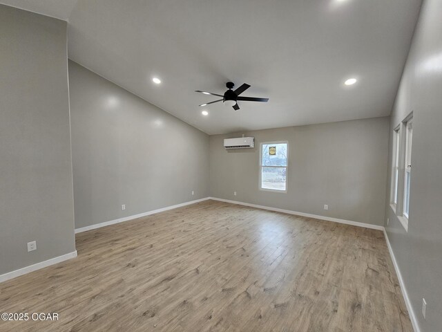 unfurnished room featuring a wall mounted air conditioner, light hardwood / wood-style floors, and ceiling fan