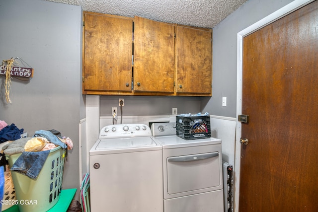 laundry area featuring cabinets, separate washer and dryer, and a textured ceiling