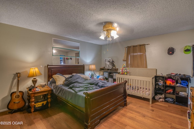 bedroom with ceiling fan, a textured ceiling, and light hardwood / wood-style flooring