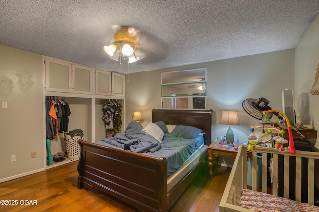 bedroom featuring a textured ceiling, a closet, ceiling fan, and dark wood-type flooring