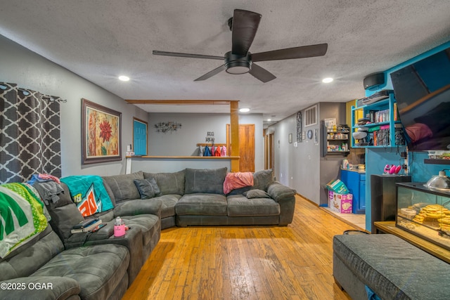 living room with ceiling fan, light hardwood / wood-style flooring, and a textured ceiling