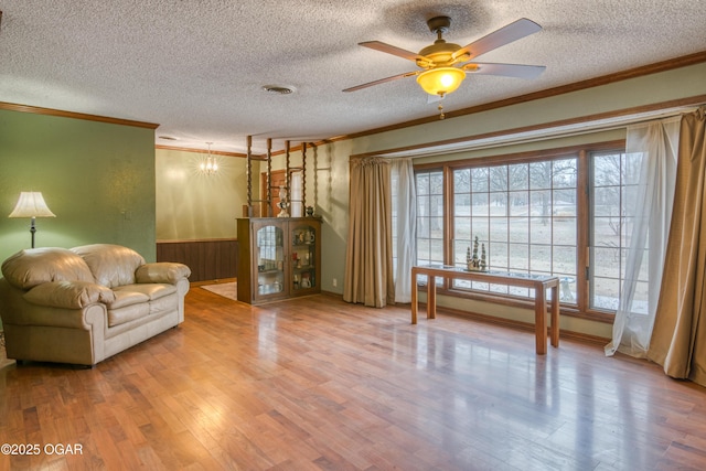 living room with crown molding, ceiling fan, wood walls, and hardwood / wood-style flooring