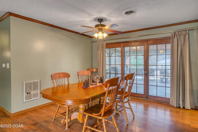 dining space with heating unit, crown molding, a textured ceiling, ceiling fan, and light hardwood / wood-style floors