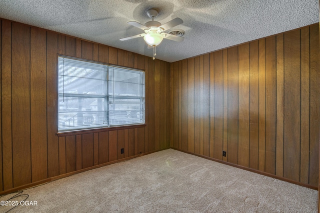 carpeted empty room with ceiling fan and wood walls