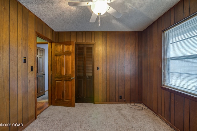 bedroom featuring multiple windows, light colored carpet, ceiling fan, and wood walls