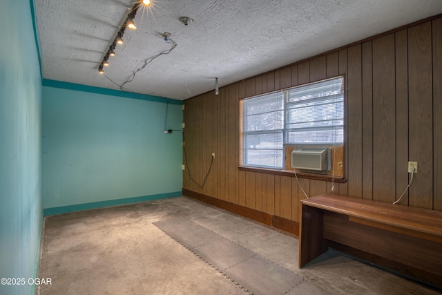 spare room featuring cooling unit, a textured ceiling, and wood walls