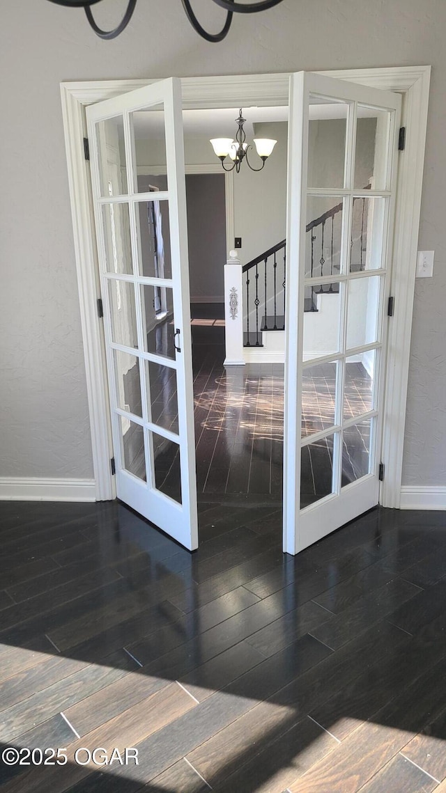 interior space featuring an inviting chandelier, dark hardwood / wood-style flooring, and french doors