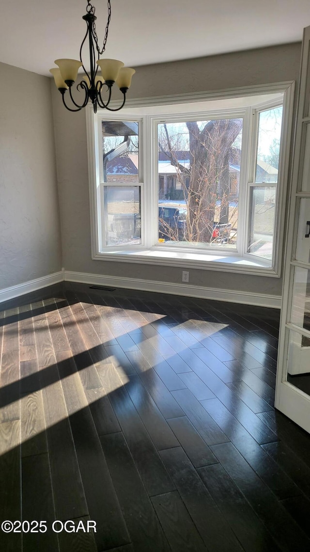 unfurnished dining area with dark hardwood / wood-style flooring and a notable chandelier