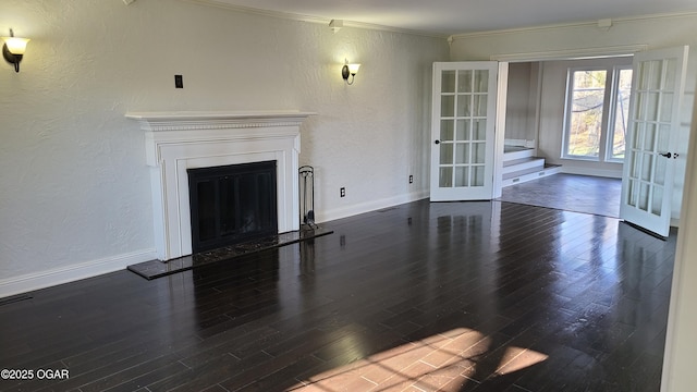 unfurnished living room with french doors, ornamental molding, and dark wood-type flooring