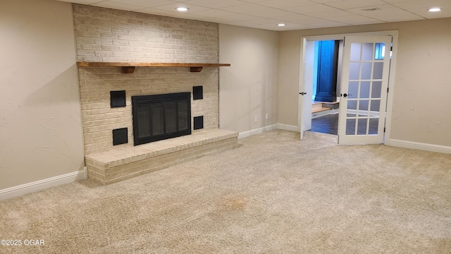 unfurnished living room featuring carpet, a paneled ceiling, and a brick fireplace