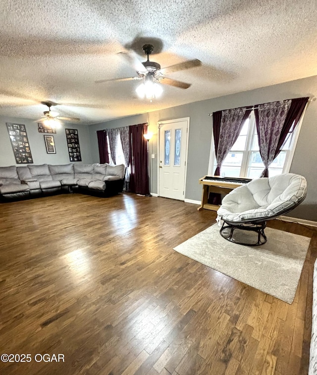 unfurnished living room with ceiling fan, a textured ceiling, dark hardwood / wood-style floors, and a healthy amount of sunlight