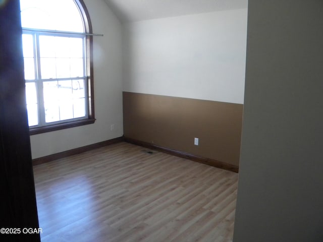 unfurnished room featuring vaulted ceiling and light hardwood / wood-style flooring