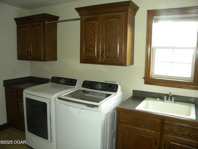 laundry room featuring washing machine and dryer, dark tile patterned flooring, sink, and cabinets