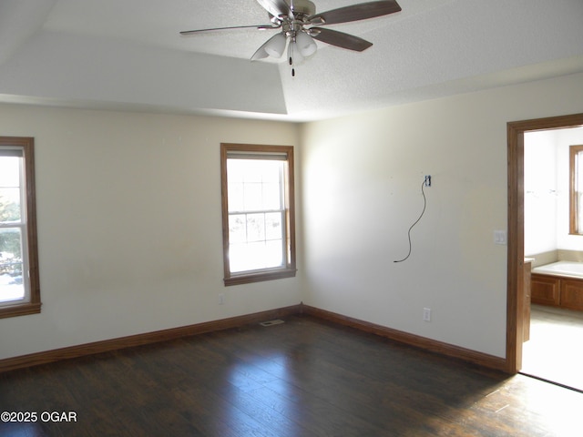 spare room with ceiling fan, dark hardwood / wood-style floors, and a tray ceiling