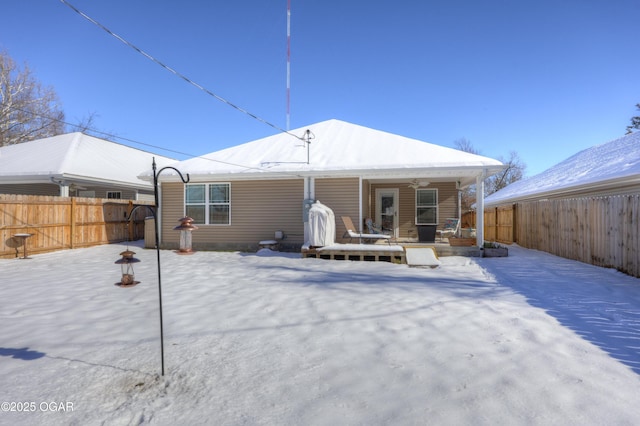 snow covered back of property featuring covered porch