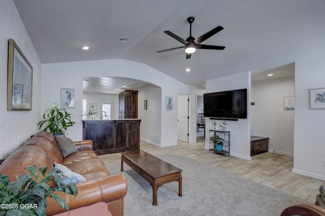 living room with ceiling fan, light wood-type flooring, and lofted ceiling