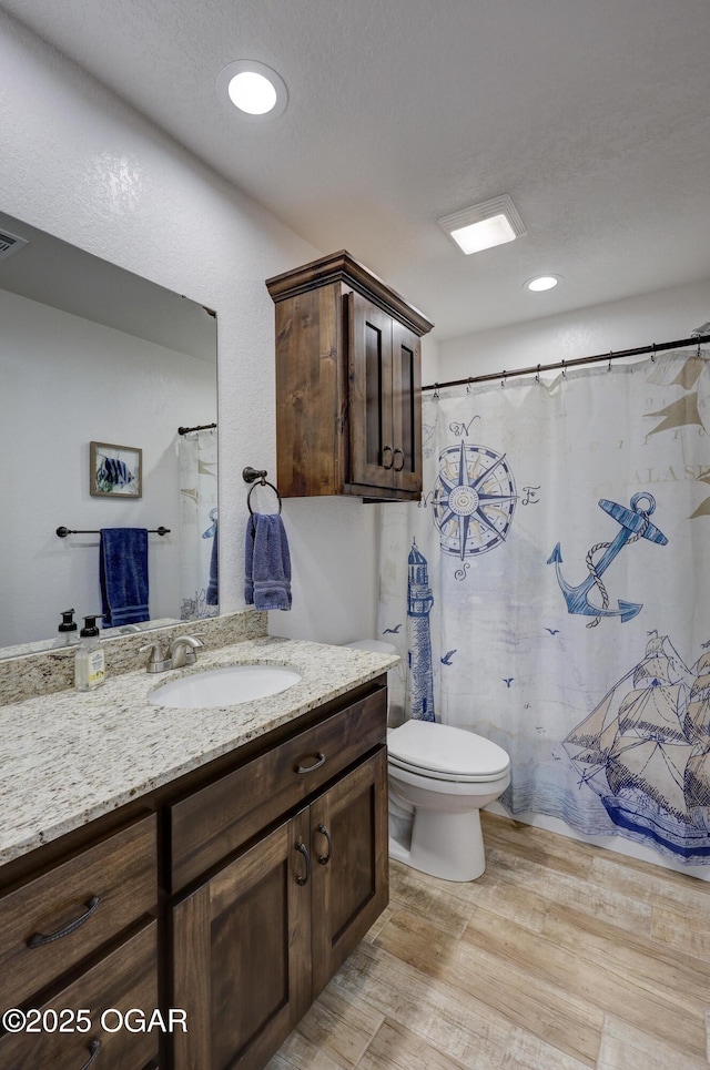 bathroom featuring toilet, vanity, and hardwood / wood-style floors